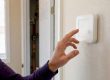 Hand holding thermostat faceplate with blank screen