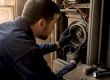 Hands inspecting blower assembly in furnace