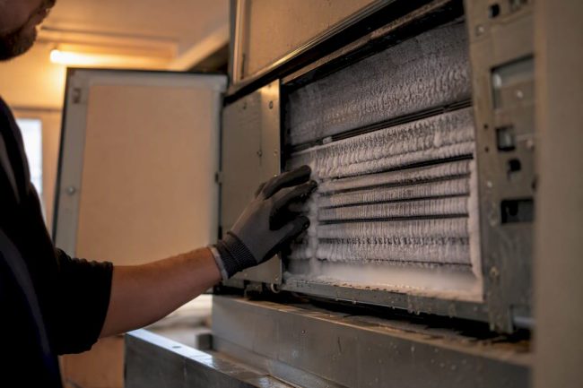 Icy indoor AC coil being inspected