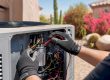 Technician testing AC capacitor in outdoor unit
