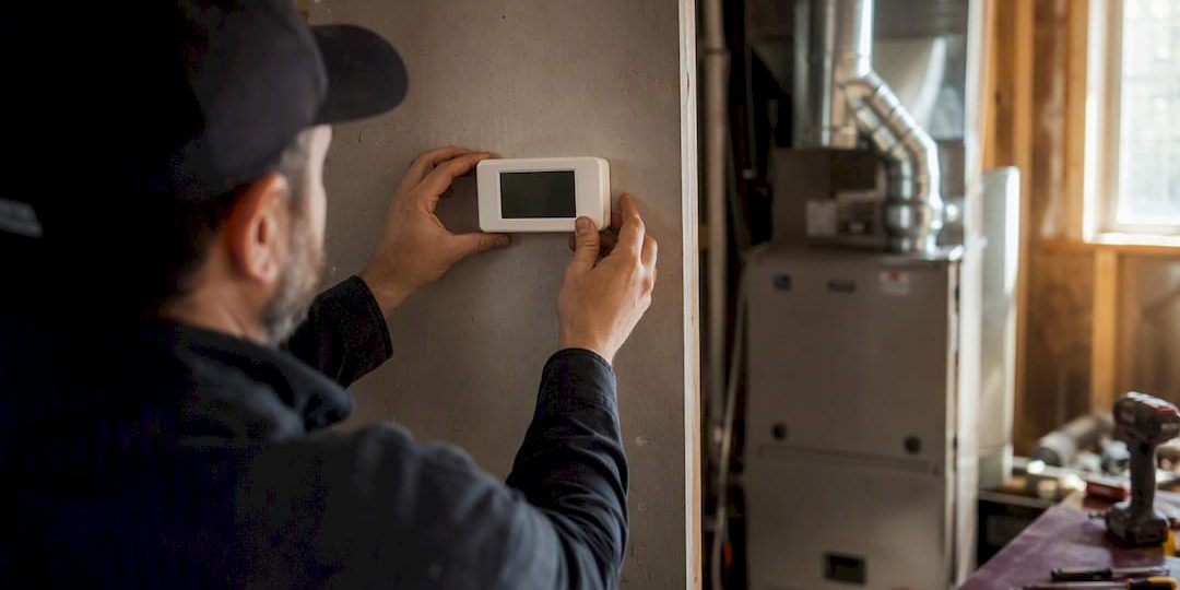1787920585228_Hands-adjusting-thermostat-with-blower-motor-background Hands adjusting thermostat with blower motor background