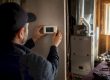Hands adjusting thermostat with blower motor background