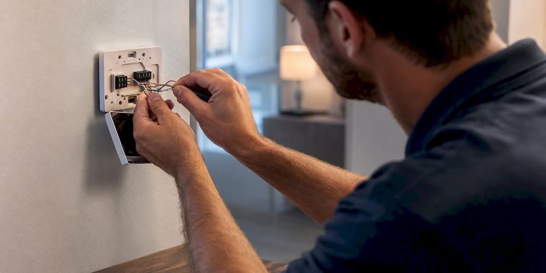 Technician connecting thermostat wiring at a wall