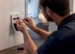 Technician connecting thermostat wiring at a wall