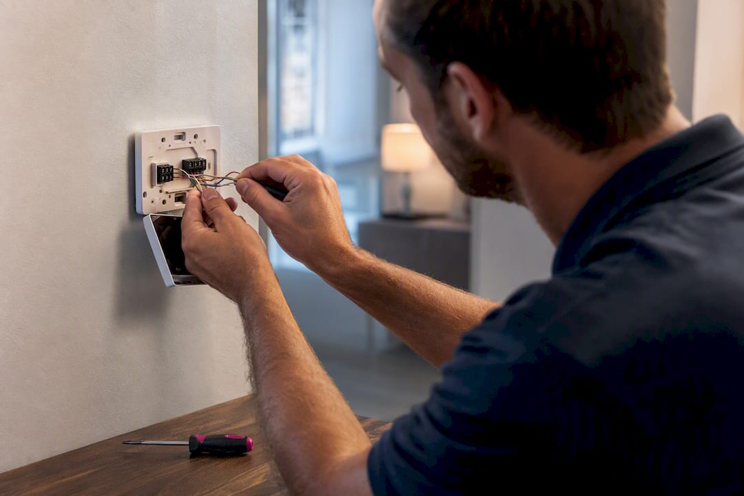 Technician connecting thermostat wiring at a wall