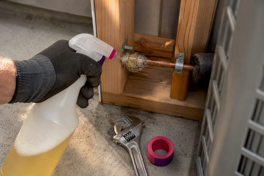 Homeowner checking AC fitting for bubbles