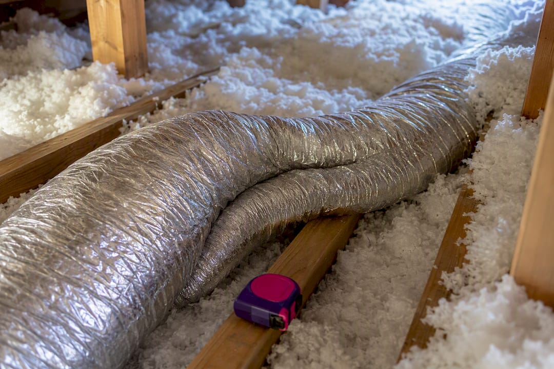 Crushed flexible duct beneath attic insulation