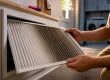 Homeowner inspecting a visibly loaded AC filter