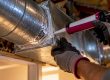 Technician sealing an exposed duct junction