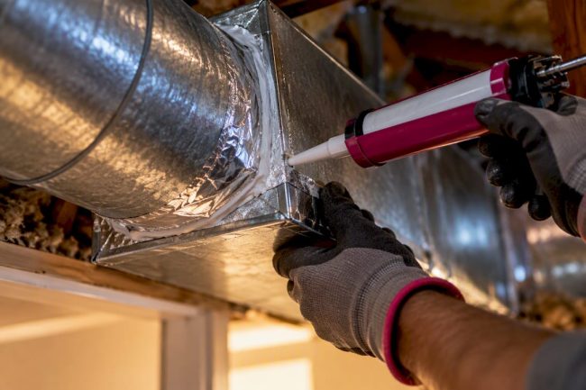 Technician sealing an exposed duct junction