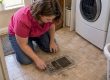 Homeowner inspecting dust around floor vent