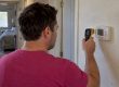Homeowner comparing thermostat and thermometer readings
