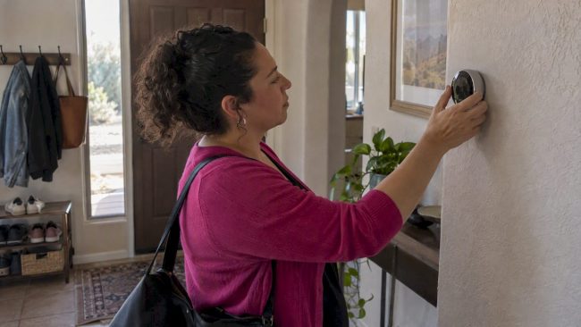 Homeowner adjusting a smart thermostat before leaving