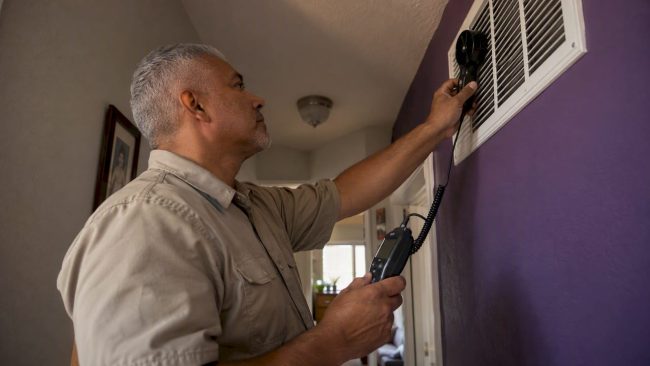 Technician measuring airflow at a return grille