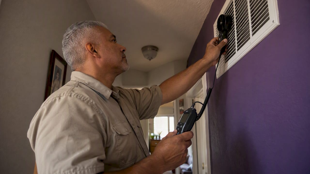 Technician measuring airflow at a return grille